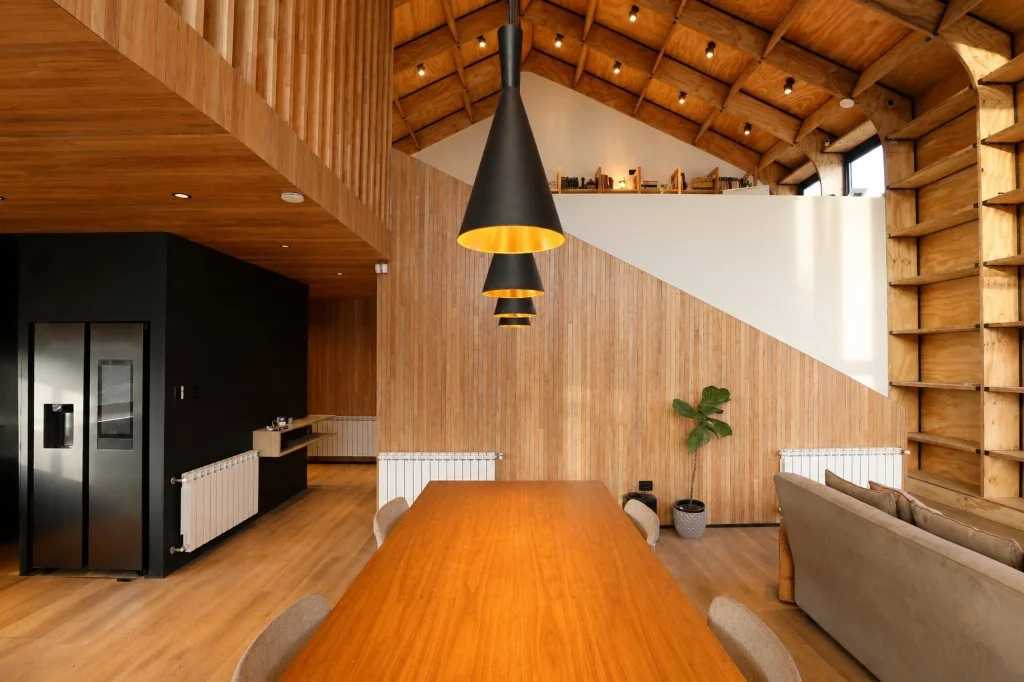 Interior de Casa Nórdica en Trevelin: comedor integrado bajo cielorraso de madera con doble altura